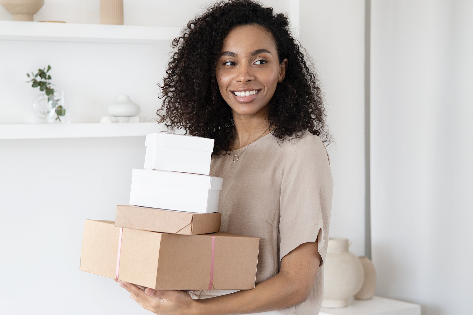 A woman holding a stack of boxes, possibly moving or organizing belongings.