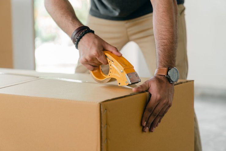 A man using a box cutter to open a cardboard box.